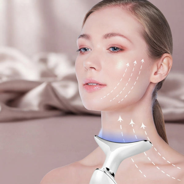 A woman using the AuraLift Pro device on her face to help serum absorb into her skin in a soft, pink-toned room.